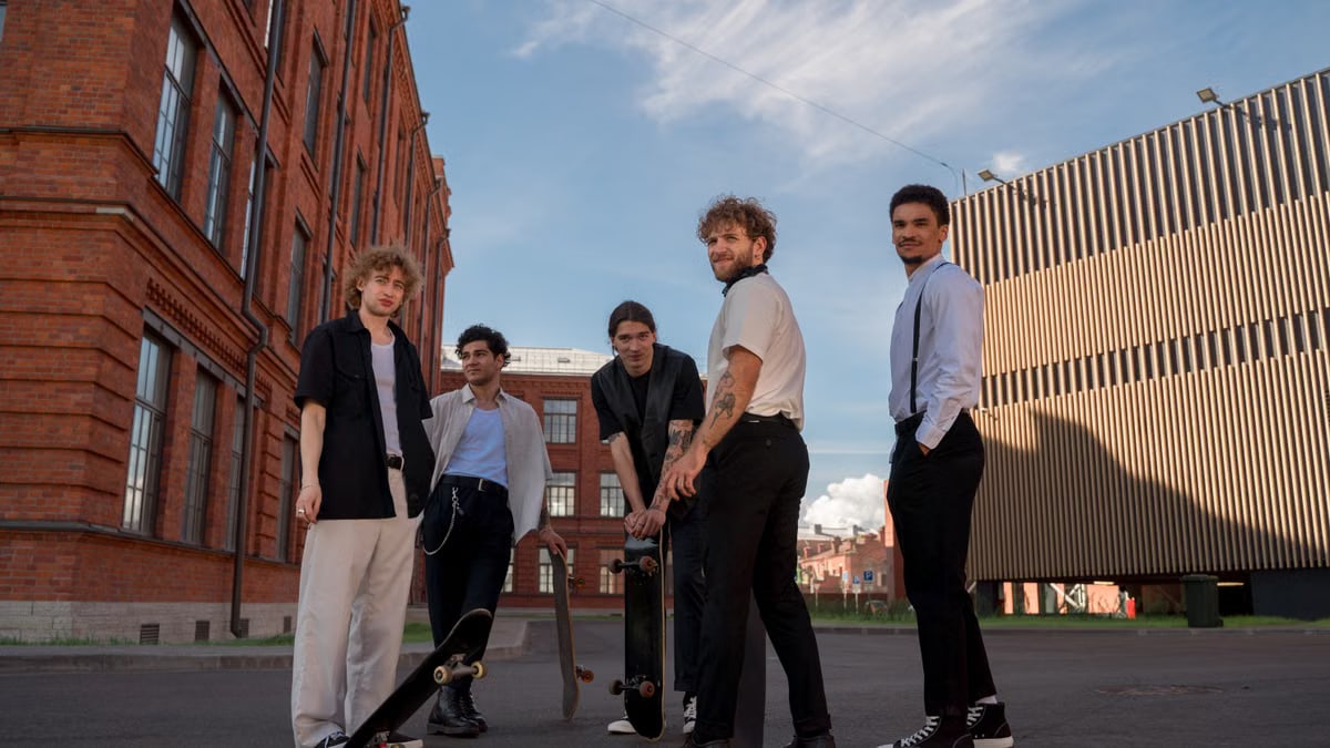A group of young adults with skateboards in an urban setting, enjoying a sunny day.
